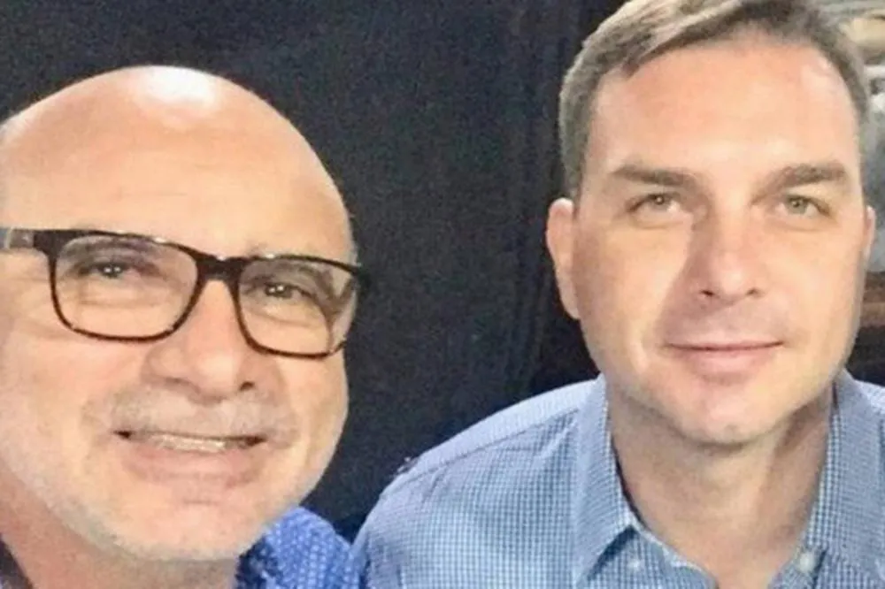 Flavio Bolsonaro e o amigo Queiroz, administrador das rachadinhas: caso poderá voltar aos debates na campanha eleitoral Reprodução
